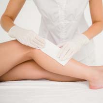 Mid section of therapist waxing womans leg at spa center